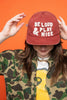 Person wearing a red cap with 'BE LOUD & PLAY NICE' text against an orange background