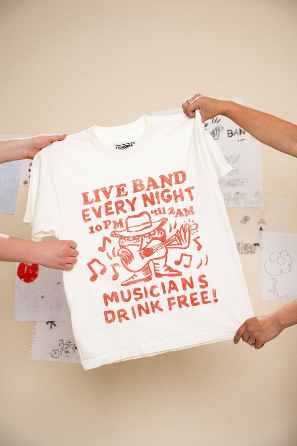 White t-shirt with red text and graphics that read "live band every night musicians drink free" held by two people against a light background