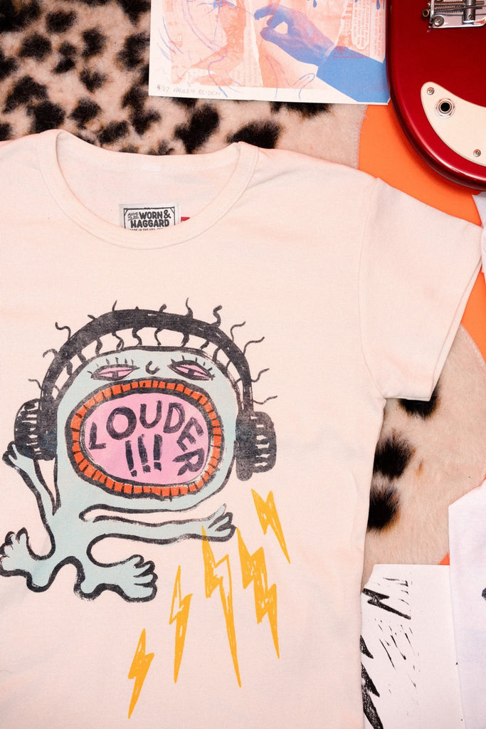 T-shirt with graphic design and text 'LOUDER' on a leopard print surface.