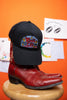 Black cap with a colorful 'Music City USA' design, on a red boot against an orange background