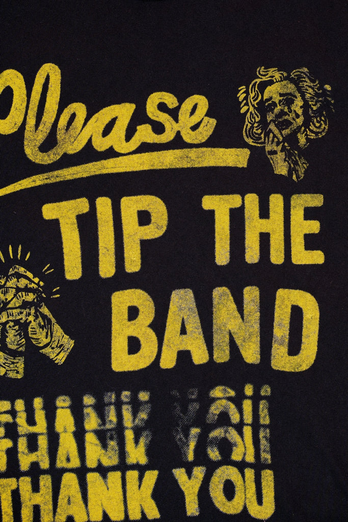 zoomed-in photo of a black t-shirt with yellow text that reads "please tip the band thank you"
