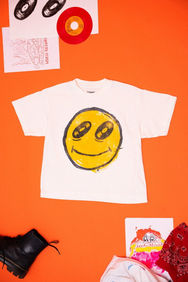 White t-shirt with smiley face design on an orange background