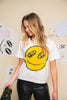 Person wearing a white t-shirt with a yellow smiley face design in an indoor setting.