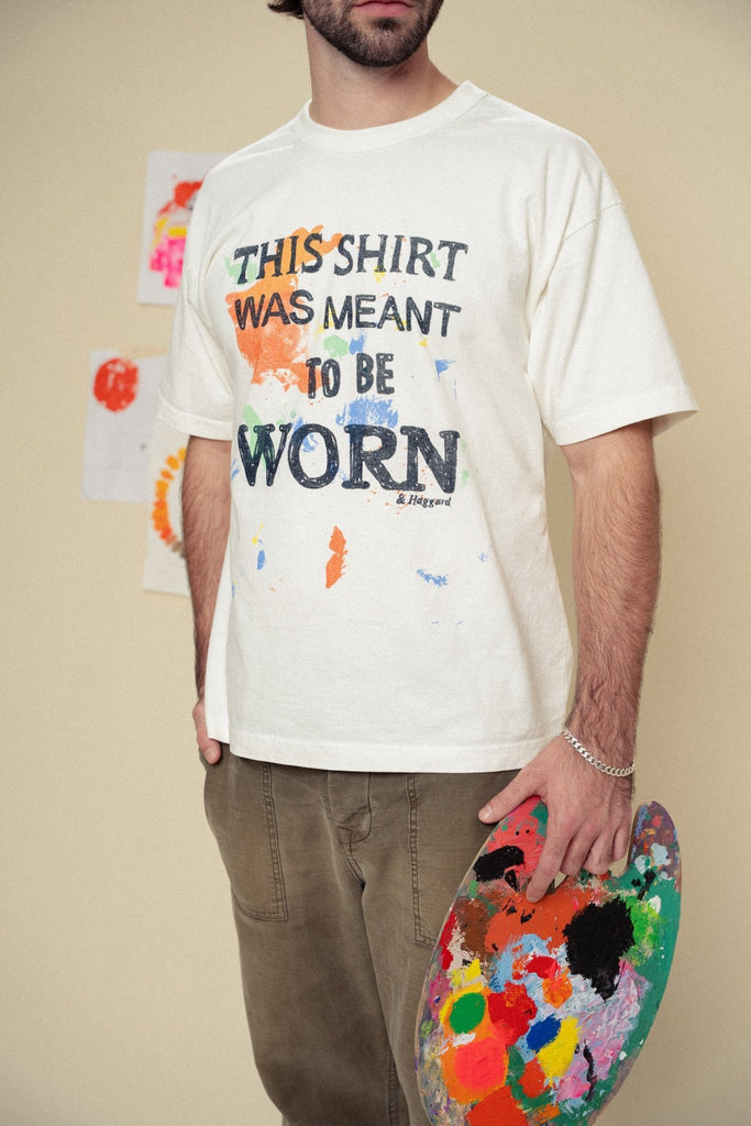 Person wearing a white t-shirt that says "this shirt was meant to be worn", holding a paint palette.