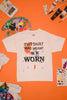 White t-shirt with text "this shirt was meant to be worn", on an orange background with art supplies.